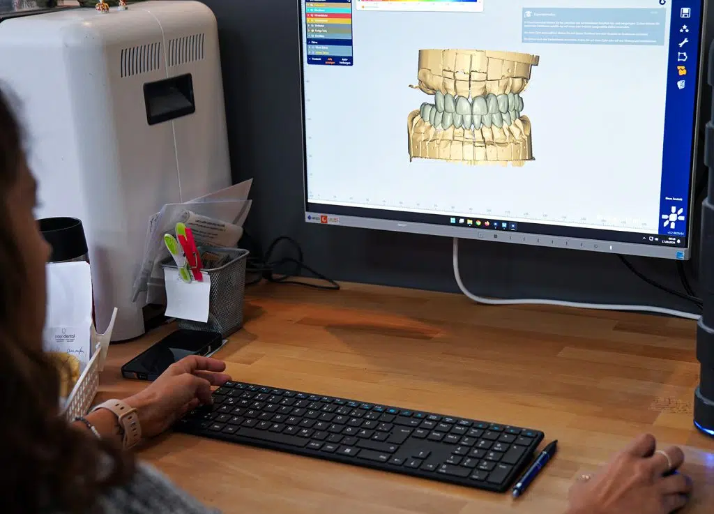 Zahntechnikerin konstruiert am Bildschirm mit CAD-Software bei inter-dental